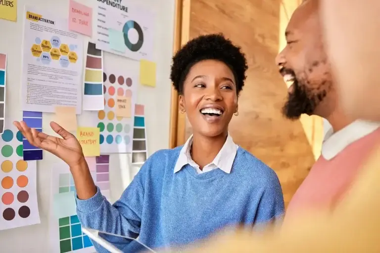 planning-group-brainstorming-and-business-people-for-branding-research-and-strategy-for-a-project-1-1webp | Lobo Digital | Lobo Digital Two coworkers in a bright office discuss color swatches and charts on a wall filled with color samples and diagrams.